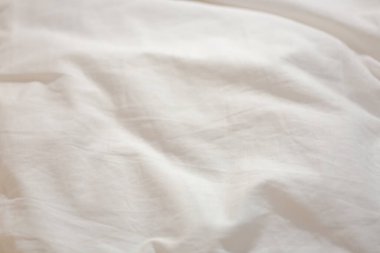 Kalıplı beyaz bir kumaş parçası. Desen görünür değil. Çarşaf katlanmış ve buruşmuş.