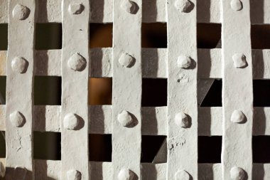 Bir sürü deliği olan beyaz bir çit. Delikler küçük ve aralıklı.