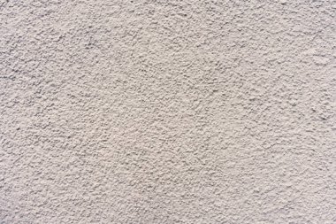 Kabataslak desenli ve açık renkli bir duvar. Duvar betondan yapılmış ve grimsi bir rengi var.