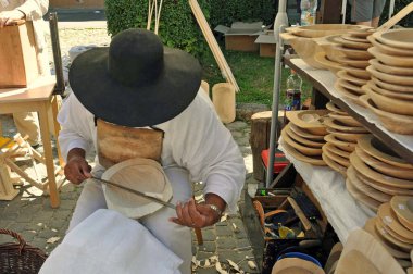 Bir folk sanatçısı ve marangoz, Slovakya 'nın Kemarok kentindeki Avrupa Halk Sanatları Fuarı ELRO' sunda ahşap kaplar yapmak için el aletleri kullanıyor..