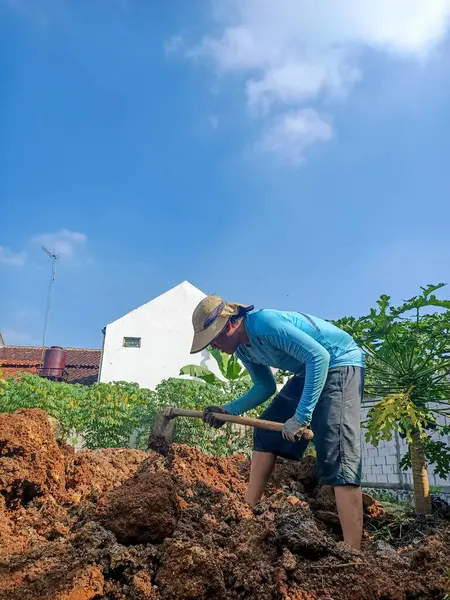 When the weather was shining, a man worked hard to hoe a lot of land in front of him