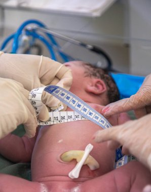 Doktor yenidoğan üzerinde ölçüm yapıyor.