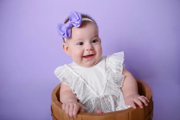बाळ मुलगी पोझिंग आणि स्मित जांभळा पार्श्वभूमी स्टॉक इमेज