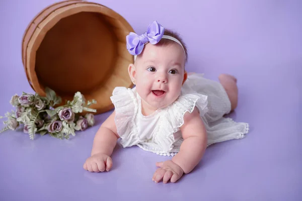 बाळ मुलगी पोझिंग आणि स्मित जांभळा पार्श्वभूमी विना-रॉयल्टी स्टॉक फोटो