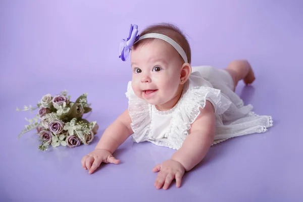 बाळ मुलगी पोझिंग आणि स्मित जांभळा पार्श्वभूमी स्टॉक फोटो