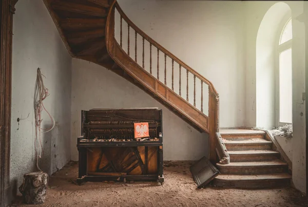 a piano in a run down room with a staircase
