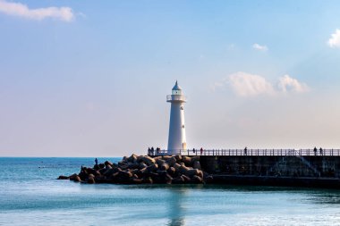 Mavi gökyüzü ve deniz feneri olan bir manzara.