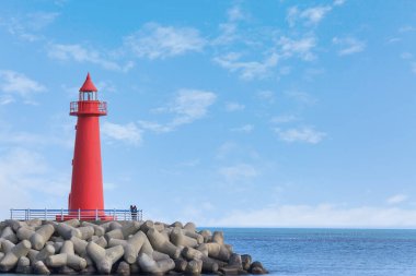 Mavi gökyüzü ve deniz feneri olan bir manzara.