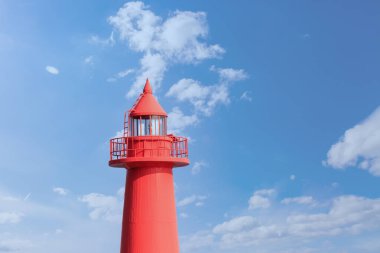 Mavi gökyüzü ve deniz feneri olan bir manzara.