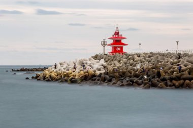 Deniz feneri ve dalgalı suyu olan bir deniz sahnesi