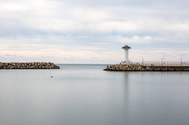 Deniz feneri ve dalgalı suyu olan bir deniz sahnesi