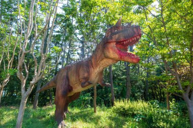 Dinozor heykelleri olan bir orman parkı manzarası