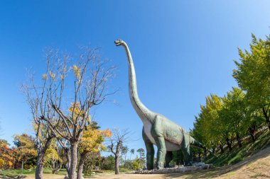 a view of a forest park with dinosaur sculptures clipart