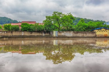 Çiftlik için su toplanan pirinç tarlalarına yansıyan ev ve köylerin yansıması