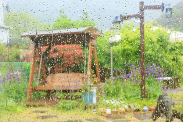 Baharda, yağmurda ıslanmış ağaçlar ve çiçeklerle parkın yürüyüş yolu manzarası.