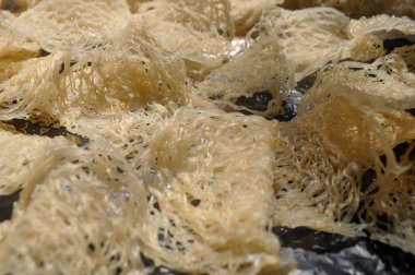 Bu resimde, kurumuş ip cambazları basit ama ilgi çekici bir kompozisyonda sergileniyor. Düzgünce düzenlenmiş ince, narin erişte dizileri eşsiz dokularını ve şekillerini sergileyerek sergileniyor. Kurumuş ipin soluk, sessiz tonları.