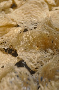 Bu resimde, kurumuş ip cambazları basit ama ilgi çekici bir kompozisyonda sergileniyor. Düzgünce düzenlenmiş ince, narin erişte dizileri eşsiz dokularını ve şekillerini sergileyerek sergileniyor. Kurumuş ipin soluk, sessiz tonları.