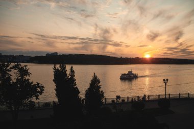 Tekne gölde yüzüyor... arka planda... güzel renkli gökyüzünün... günbatımında ve şehir manzarasında.
