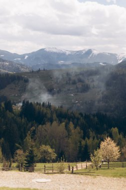 Uzakta bulutlu bir gökyüzü ve dumanı olan bir sıradağ.