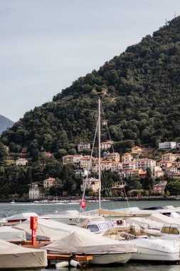 A group of boats are docked in a marina, with a red and white sign on the water. The boats are of various sizes and colors, and the scene is peaceful and serene clipart