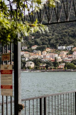 Üzerinde bir kasaba olan bir dağ ve arka planda bir su kütlesi. Kasaba küçük ve bir sürü evi var. Çitteki bir işaret insanları suda yüzmemeleri için uyarıyor. Su sakin ve şehrin manzarası çok güzel.