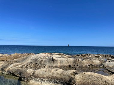 Sakin kumsal sahnesi berrak gökyüzü, sakin dalgalar ve altın kum.