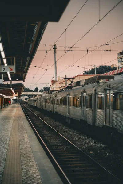 A low-key lighting shot was taken in a train station, on the edge between the yellow safety line and the railroad track; on one of the tracks, a train that stopped at the stop in question at nightfall