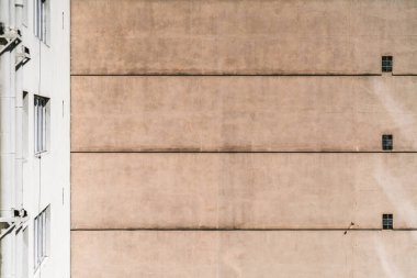 View of a plastered building elevation wall with a pattern of floor lines and windows; a texture of a house facade on a bright day