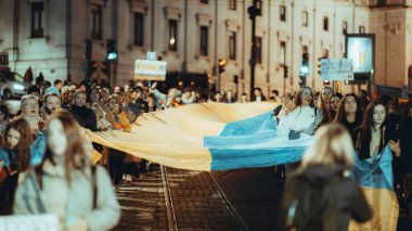 Lisbon, Portugal - February 24, 2023: Low-key shot of members of the Ukrainian and Russian communities in Lisbon, holding the Ukrainian flag during the one-year anniversary of the war in Ukraine