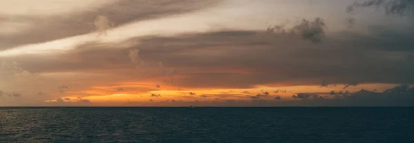 一片迷人的橙色落日笼罩在宁静的海岸线上 背后是一片灰蒙蒙的云彩 消失在寂静的夜色中 一片令人叹为观止的全景 — 图库照片