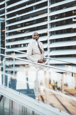 Lizbon 'daki dikey çekimde, beyaz sakallı, kel, şık beyaz takım elbiseli ve renkli çizgili kravatlı bir siyah adam yer alıyor. Kusursuz bir cam korkuluğun yanında duruyor, entelektüellik saçıyor.