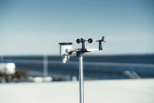 A sleek wireless weather station made in a metallic material has some black and white spots and provides accurate weather information against a dreamy defocused blue skies