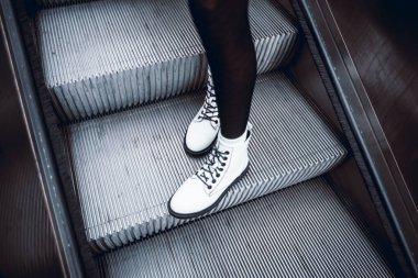 Şık şehir adımları, bir çift şık beyaz kadın botla yürüyen merdivenden aşağı iniyor. Siyah çoraplı bir kızın şık bir ayakkabısı..