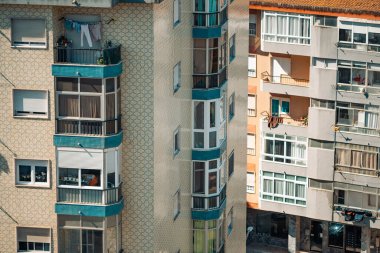 Lizbon 'daki apartman binalarının ayrıntılı manzarası. Karmaşık fayanslı cepheler ve balkonlar. Görüntü, şehir mimarisini yakalıyor, çamaşırları bir balkondan sarkıyor, günlük şehir hayatı.