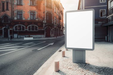 Kırmızı-turuncu ön cepheli tarihi bir binanın önündeki kaldırım taşı caddesinde boş bir reklam panosu modeli duruyor. İlan panosu boş, reklam için hazır, güneş ışığı gölgeleri bırakıyor.