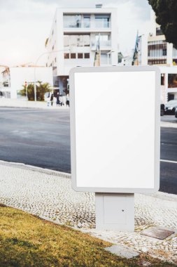 Modern binaların ve işlek bir caddenin önündeki kaldırımda duran boş, dikey bir reklam panosunun şablonu. Model kentsel bir ortamda reklam için hazır; Leiria