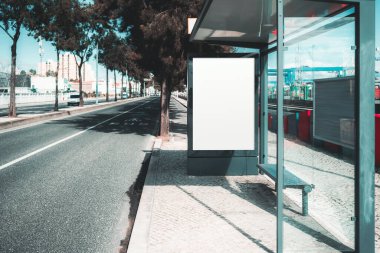 Modern bir otobüs durağında cam duvarları olan boş reklam panosu modeli. Arka planda bisiklet yolu, ağaçlar ve binalar olan şehir caddesi. Reklam tasarımı için ideal. Bir açık hava reklam şablonu