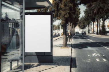 Otobüs durağında reklam için boş bir reklam panosu var. Ağaçlarla kaplı yolu, bisiklet şeridi ve camlara yansıyan yansıması olan modern şehir manzarası. Markalaşma ya da promosyon tasarımı için ideal