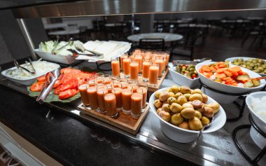 Sıcak ışık altında çeşitli sebzeler, turşular, zeytinler, domatesler, lahana, soğan, peynir ve gazpacho kadehleriyle taze bir büfe.