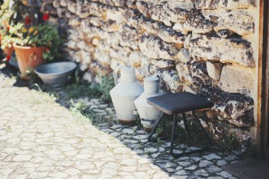 Taştan dokuması olan taşralı bir duvar, klasik metal süt kutuları, güneş ışığında parke taşından yapılma teras kapları kırsal alanda Aldeia da Mata Pequena