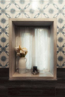 Saf beyaz perdeleri olan zarif bir iç pencere köşesi, bir sürahi kalla zambağı, ve çakıl taşları ve bir mum ile camdan bir vazo. Geleneksel Portekiz mavi seramik zemin cazibesini artırır