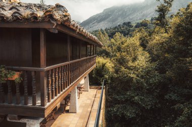 Asturias 'taki kırsal ahşap horreo geleneksel fayanslı çatı, uzun balkon ve sisli dağ manzarasına karşı manzaralı orman manzaralı, huzurlu kırsal inzivaya çekilmiş konforlu bir dağ evine dönüştü.