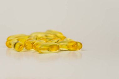 Omega-3 zengini vahşi somon ve balık yağı kapsülleri yumuşak, soluk-beyaz arka planda sunuluyor..