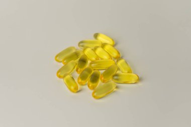 Omega-3 zengini vahşi somon ve balık yağı kapsülleri yumuşak, soluk-beyaz arka planda sunuluyor..