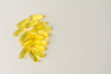 Omega-3 zengini vahşi somon ve balık yağı kapsülleri yumuşak, soluk-beyaz arka planda sunuluyor..
