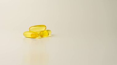 Omega-3 zengini vahşi somon ve balık yağı kapsülleri yumuşak, soluk-beyaz arka planda sunuluyor..