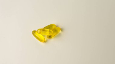Omega-3 zengini vahşi somon ve balık yağı kapsülleri yumuşak, soluk-beyaz arka planda sunuluyor..