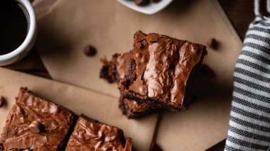  Çikolata parçalı brovniler, kahve ve çikolata parçacıkları, çatal ve bıçakla ahşap bir tahta ve biraz da kağıt..