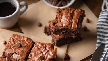  Çikolata parçalı brovniler, kahve ve çikolata parçacıkları, çatal ve bıçakla ahşap bir tahta ve biraz da kağıt..
