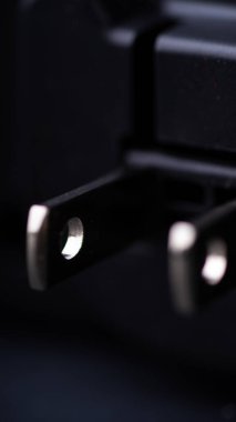 Siyah arkaplandaki şarjlı elektrik prizinin yakın plan görüntüsü.